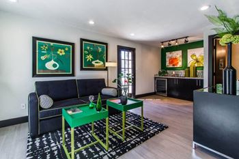 A living room with a black couch and green tables